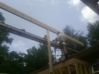 Carpenter setting a ridge beam over a new addition frame — Ice Dam Removal by Roofing Brothers in Humarock