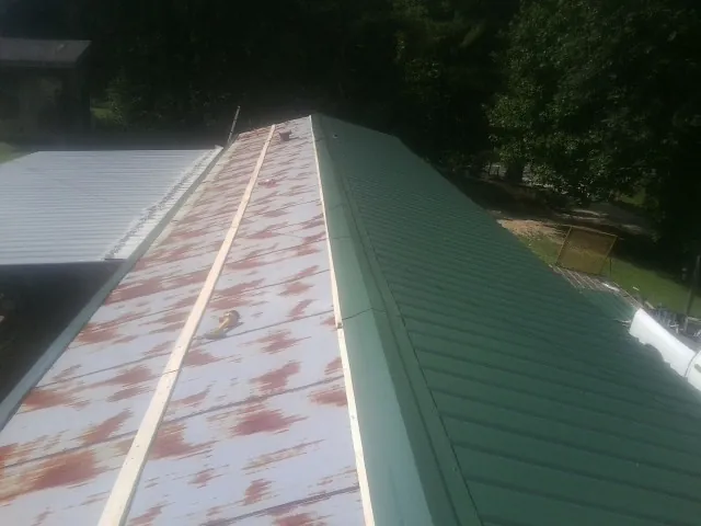 Old rusted panels beside newly installed green metal roofing — Wind Damage Roof Repair by Roofing Brothers in Humarock