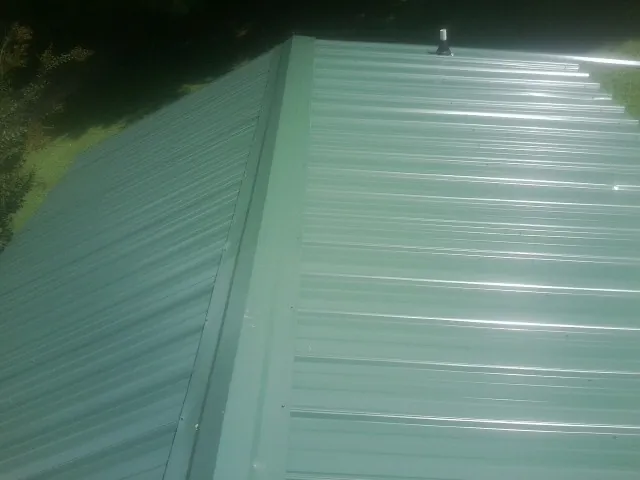 New green metal panels meeting at the ridge of a roof — Flat Roof Repair work by our crew in Humarock