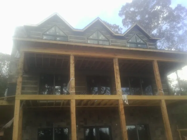 Dormers and porch framing on a large log home under construction — Roof Coating work by our crew in Humarock