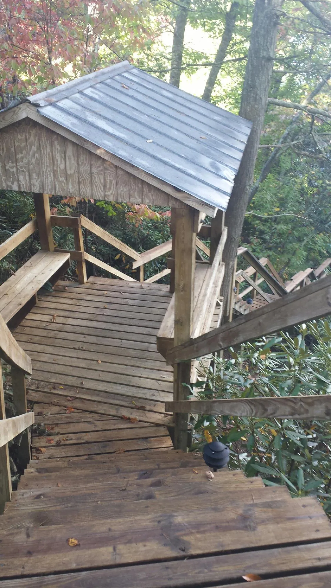 Metal roofed shelter over wooden steps on a wooded walkway — Skylight Repair & Installation work by our crew in Humarock