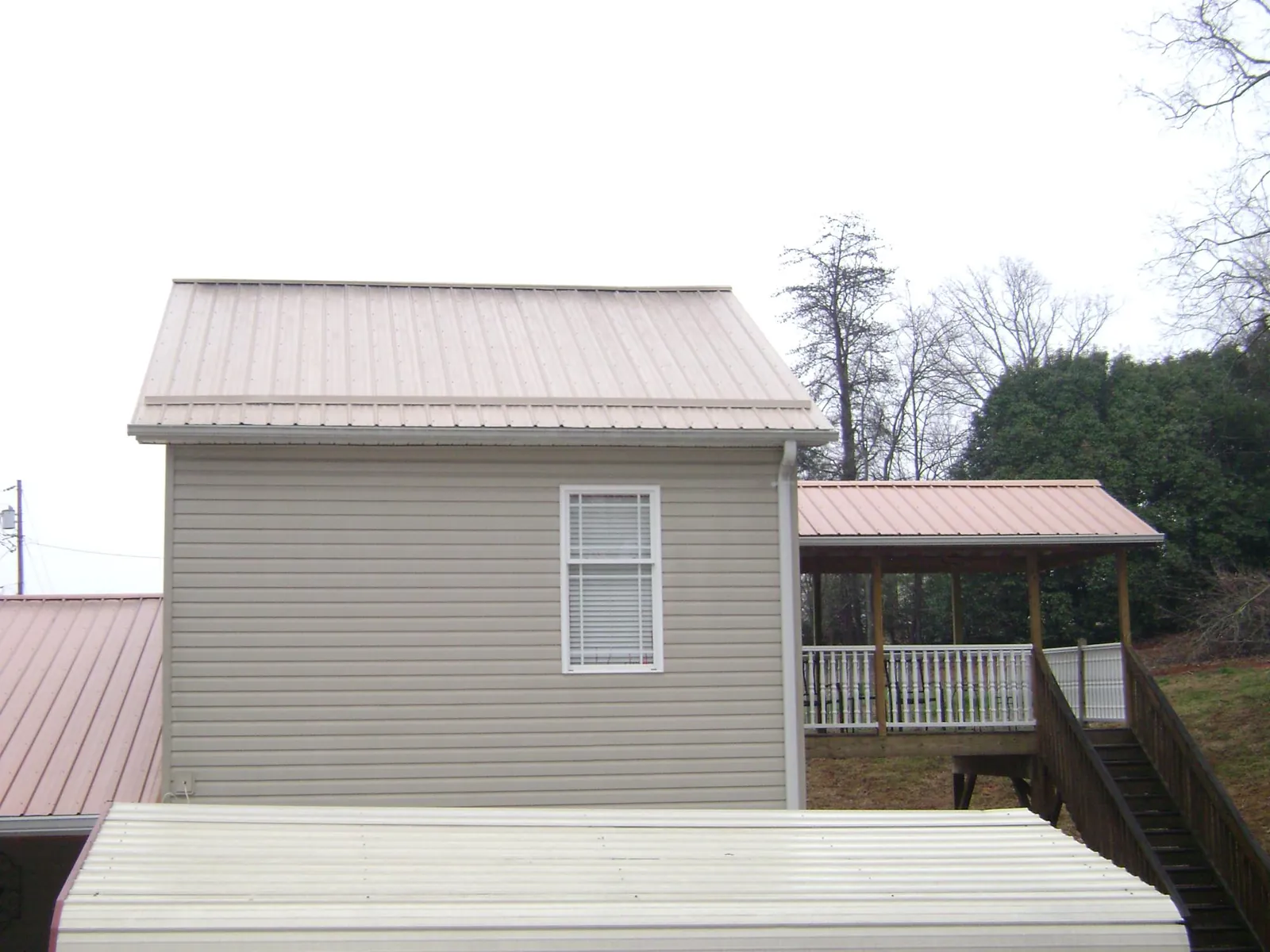 Tan metal roofs on a two story addition and attached porch, from a Roof Replacement job in Humarock