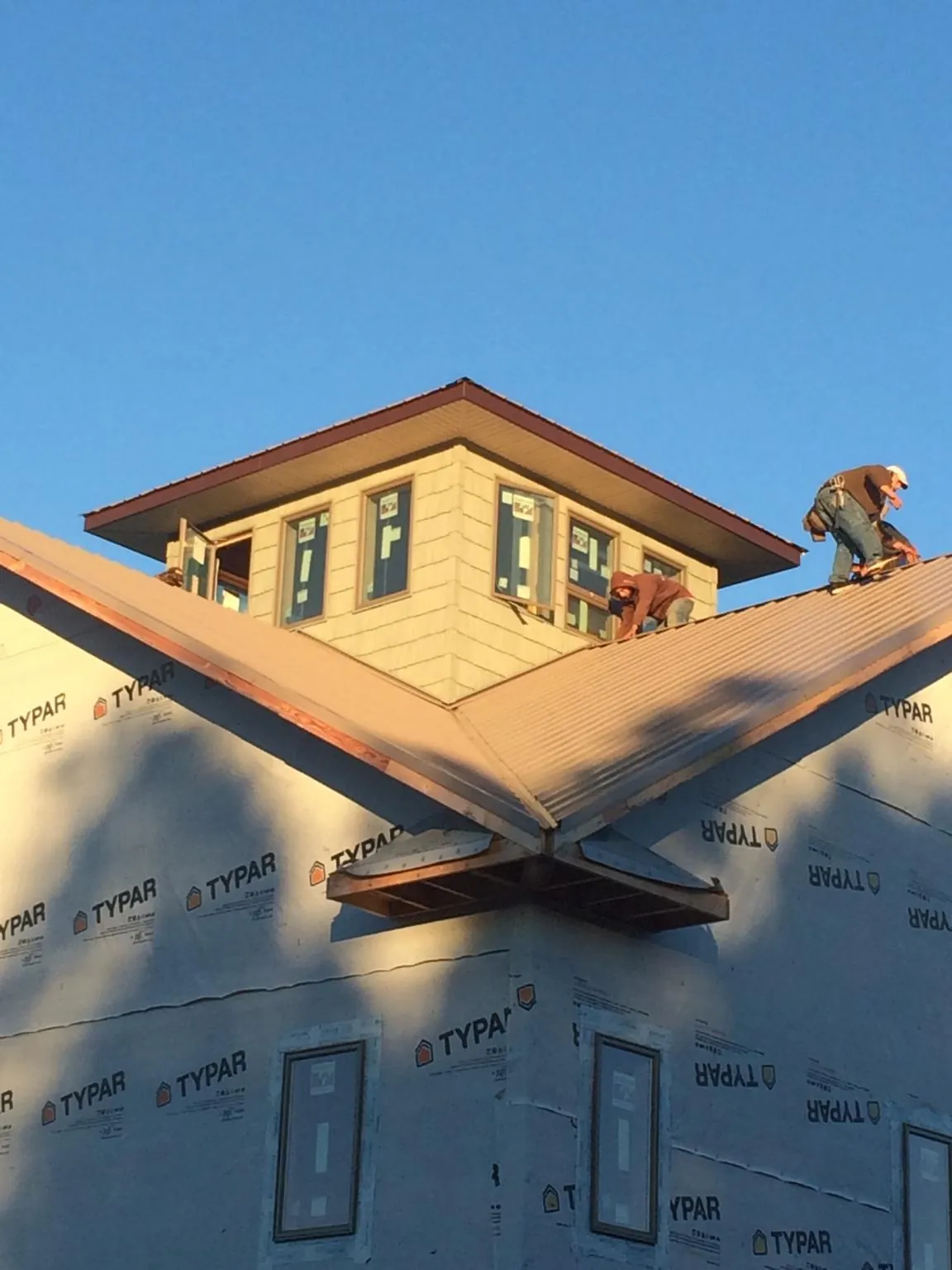 Roofers working around a rooftop cupola on a new metal roof at sunset — Roof Waterproofing in Humarock by Roofing Brothers